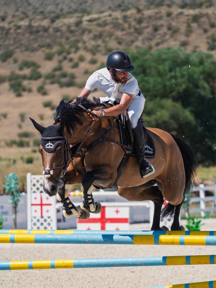 A skilled rider and horse demonstrate impressive jumping skills in an outdoor equestrian event.